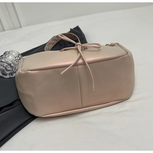 Detail of nude pink dumpling tote bag featuring soft matte leather and decorative drawstring bow