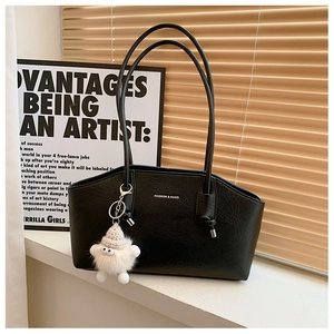 Détail du sac cabas en similicuir noir avec texte blanc et breloque monstre en peluche