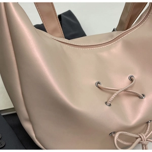 Detail of satin hobo bag with side lace-up design and silver metal eyelets