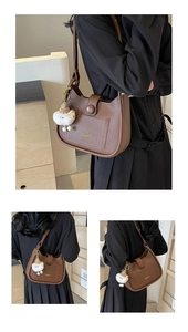 Close-up of brown leather hobo bag with gold lettering and cute white plush charm