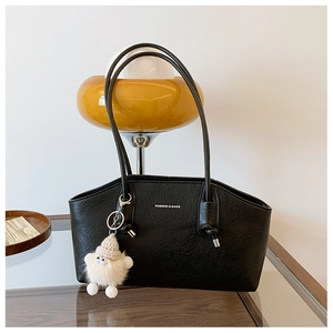 Détail du sac baguette noir texturé avec logo FASHION & BAGS et charmant pendentif peluche