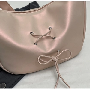 Detail of champagne pink satin dumpling bag with decorative cross-ribbon and bow