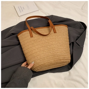 Close-up of beige woven tote bag with brown leather handles and textured straw pattern