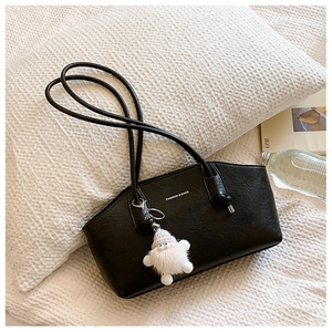 Détail du cabas en cuir noir texturé avec logo blanc et breloque en peluche douce