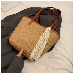 Detail of hand-woven straw tote with brown faux leather straps and white lace trim
