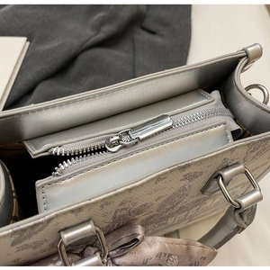 Detail der silbernen Handtasche mit Blumendruck, Logo und lila Seidenschleife am Griff