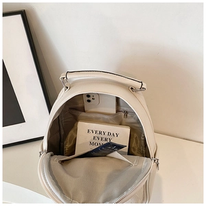 Interior view of white PU leather backpack showing organized compartments and daily essentials