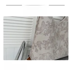 Close-up of light grey tote bag showing detailed 3D rose embossing and fine stitching texture