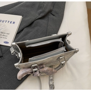Detail der grauen Handtasche mit doppelten Reißverschlussfächern und Seidenschal-Akzent