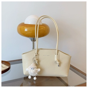 Détail du sac crème en cuir plissé avec pendentif en peluche et bandoulière