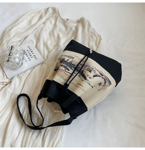 Details der gestrickten Beuteltasche mit Kunstdruck und breitem Schultergurt im Fokus