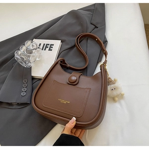 Detailed view of brown leather bucket bag with gold lettering and cute sheep charm