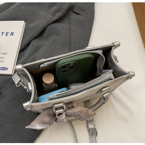 Draufsicht auf silberne Handtasche mit Innenfach für Kosmetik und Schultergurt