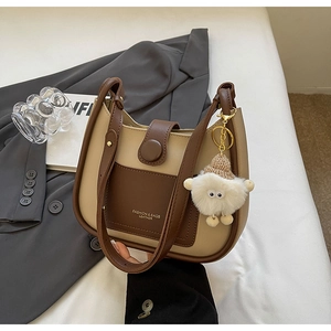 Detail of color-block bucket bag with plush sheep charm and gold-tone leather branding