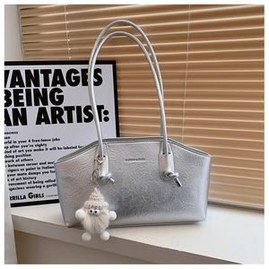 Détail du sac argenté effet froissé avec pendentif en peluche et texture métal