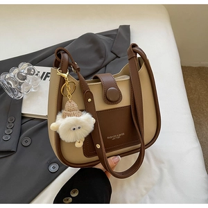 Detail of two-tone bucket bag on suit with a cute white plush sheep charm pendant