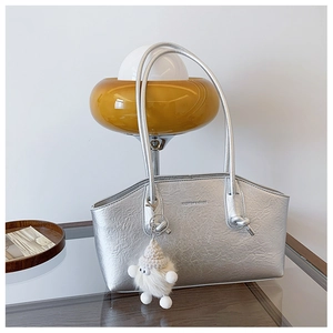 Détail du sac cabas argenté avec texture métallique froissée et breloque pelucheuse