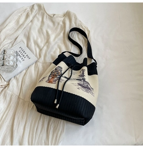 Detail der Strick-Beuteltasche mit Katzen-Illustration und Kordelzug auf weißem Rock