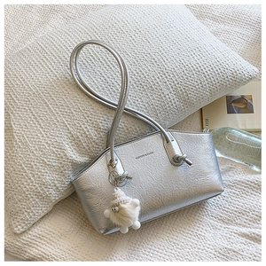 Détail du sac argenté métallisé texturé avec un joli pendentif en peluche tendance