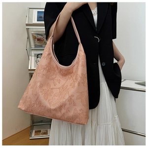 Detail of pink floral embossed leather tote bag worn as a shoulder hobo bag for women