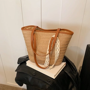 Fashionable woven straw tote bag with brown leather handles and a white lace ribbon detail
