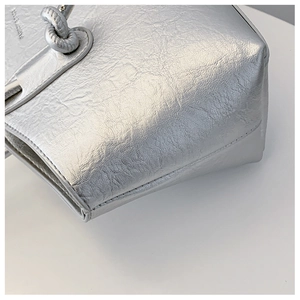 Détail d'un sac argenté avec poignée nouée et texture métallique plissée raffinée
