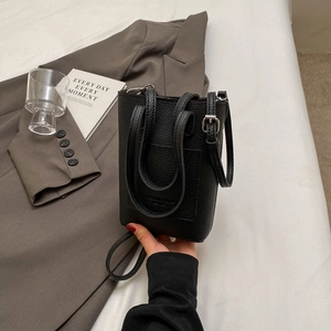 Mini sac seau minimaliste en cuir noir texturé avec bandoulière réglable pratique