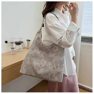 Close-up of elegant light grey tote bag featuring intricate 3D floral embroidery