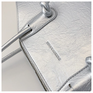 Détail du sac argenté métallisé avec texture froissée et logo FASHION & BAGS gravé