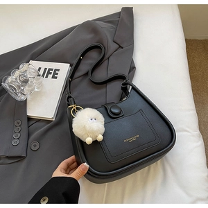 Detail of black leather saddle bag with gold lettering and white plush ball accessory