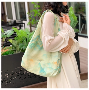 Outdoor shot of a canvas tote bag featuring classic Chinese landscape art and greenery