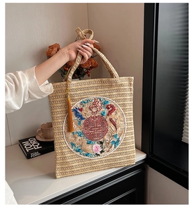 Detail of straw tote bag featuring traditional dragon phoenix embroidery and gold tassel