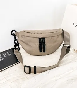 Detail of beige nylon waist bag with black chain accent and dual zipper pullers