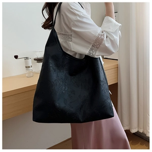 Detail of a large black tote bag featuring exquisite rose floral embossing and shoulder strap
