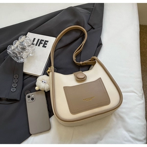 Detail of cream and khaki bucket bag featuring side plush ball charm and logo pocket