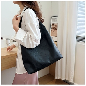 Detail of black tote bag with embossed 3D floral pattern and leather texture