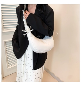 Detail of white pleated underarm bag with drawstring bow and puffy nylon texture
