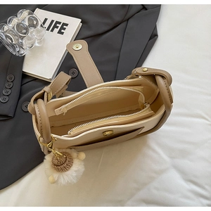 Interior view of beige bucket bag showing zip pockets and plush sheep charm detail