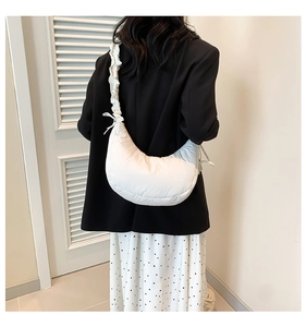 Detail of white pleated crescent bag with bow ties and puffy nylon shoulder strap