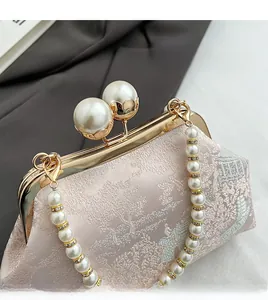 Close-up of pink jacquard silk handbag with pearl handle and golden clasp closure