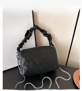 Detail of black pleated handle bag with embossed floral texture and silver chain strap