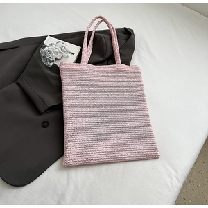 Detail of pink woven tote bag with herringbone pattern on a stylish white flat lay background