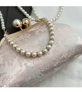 Detail of light pink silk embroidery and pearl handle with diamond-encrusted spacers