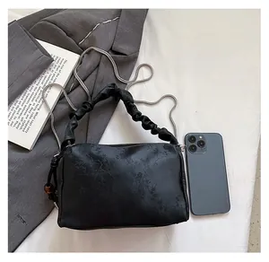 Detailed top view of black pleated handbag with silver chain and floral fabric pattern