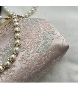 Detail showing champagne pink satin fabric with classical embroidery and pearl handle strap