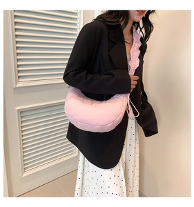 Detailed view of pink quilted crescent bag with adjustable shoulder strap and puffy fabric