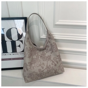 Detail of floral embossed texture on a beige faux leather tote bag with elegant relief