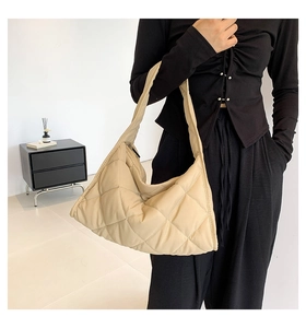 Primer plano del bolso tote beige acolchado mostrando su textura suave y correa ancha