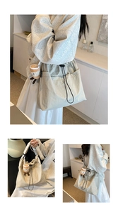Detail of a large beige tote bag featuring side pockets and a cute coffee cup charm