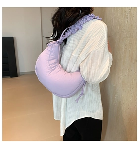Detailed view of light purple cloud bag with ruffled shoulder strap worn by model